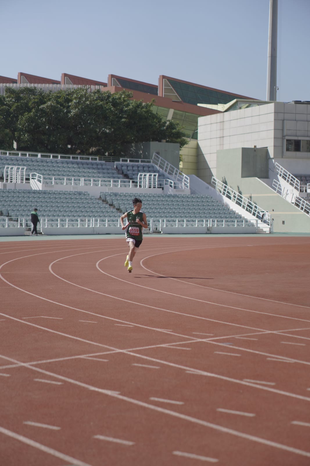 A runner accelerating along an outdoor track.