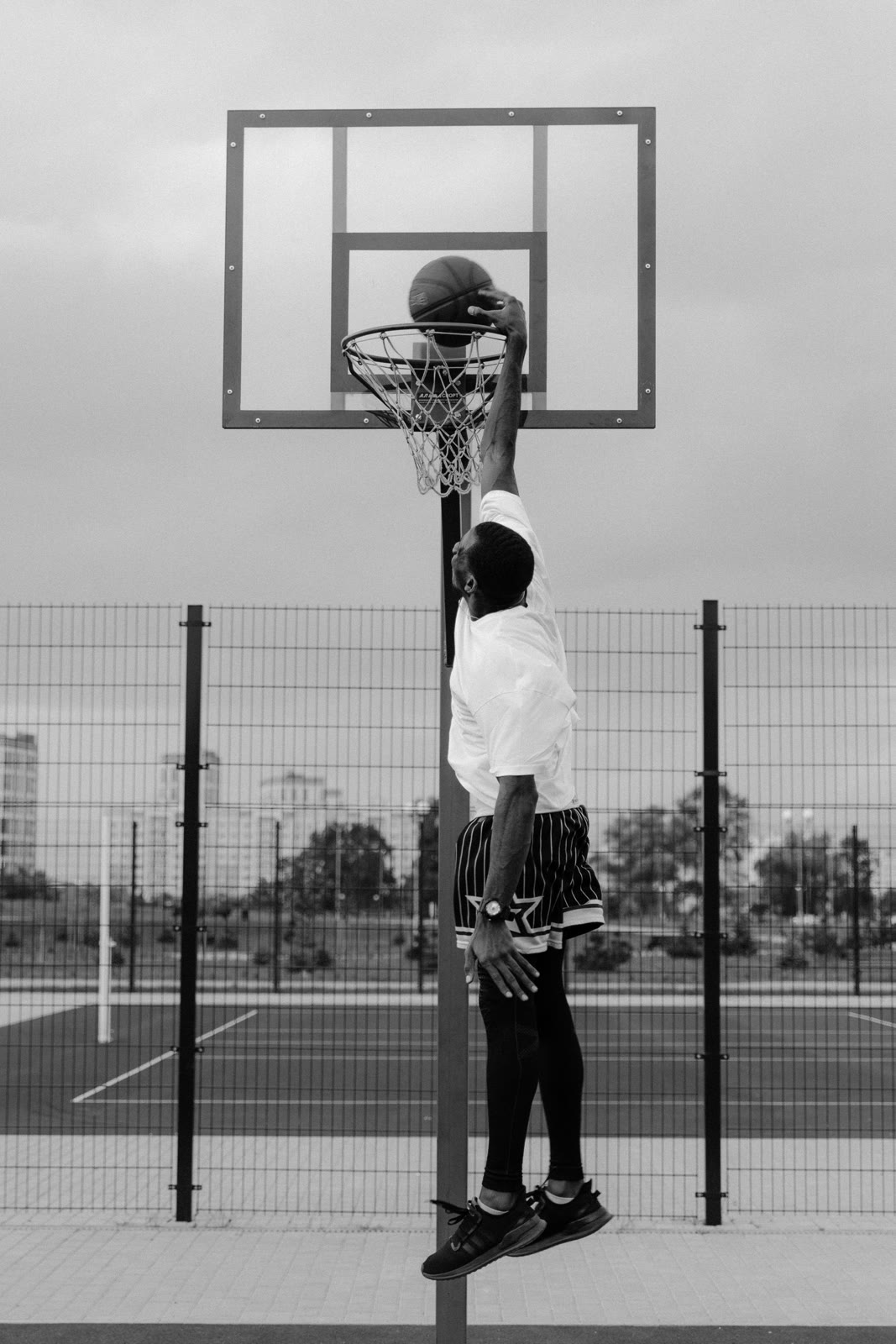 A basketball player jumping toward the hoop in black and white.