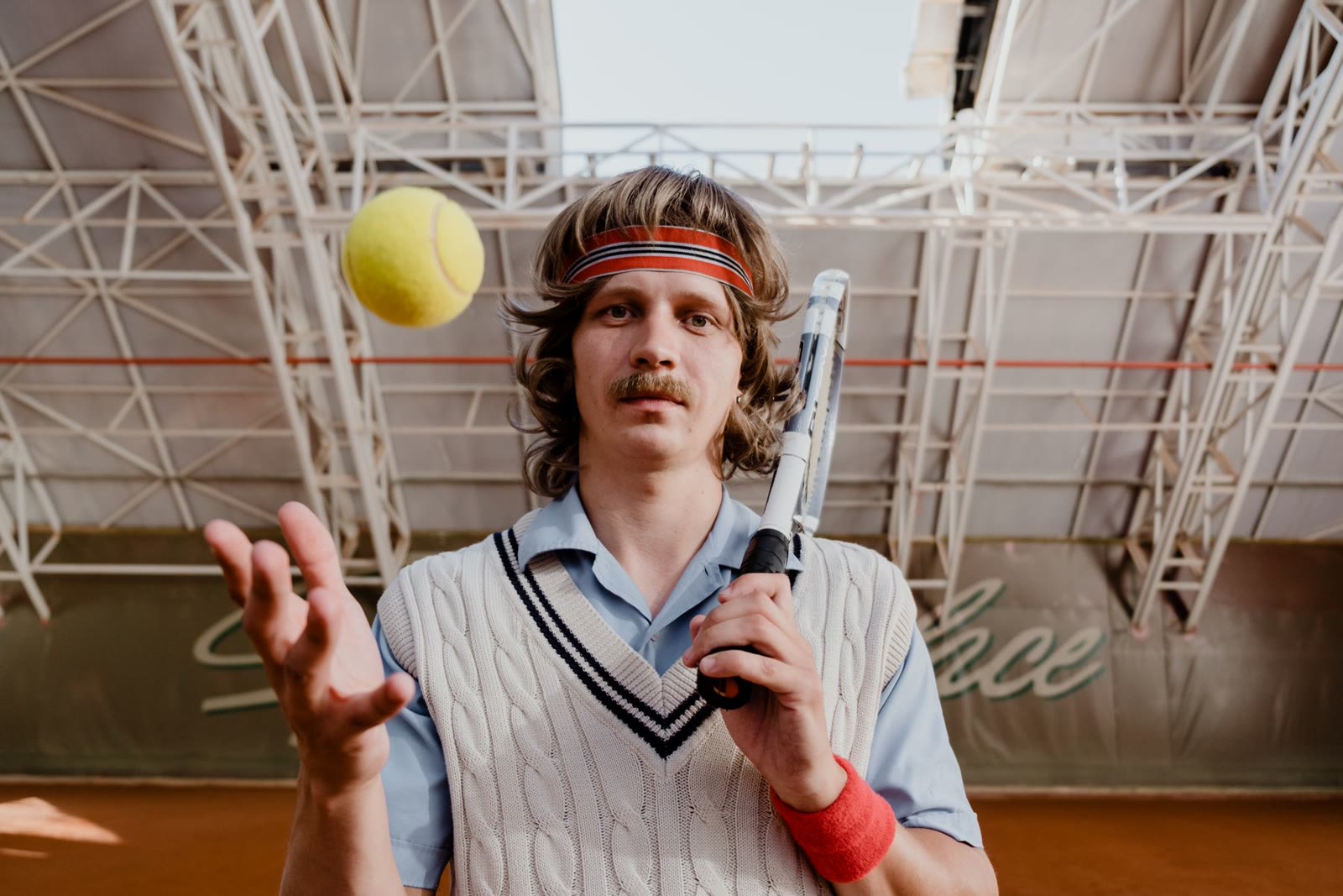 A tennis player tossing a ball above his racket.