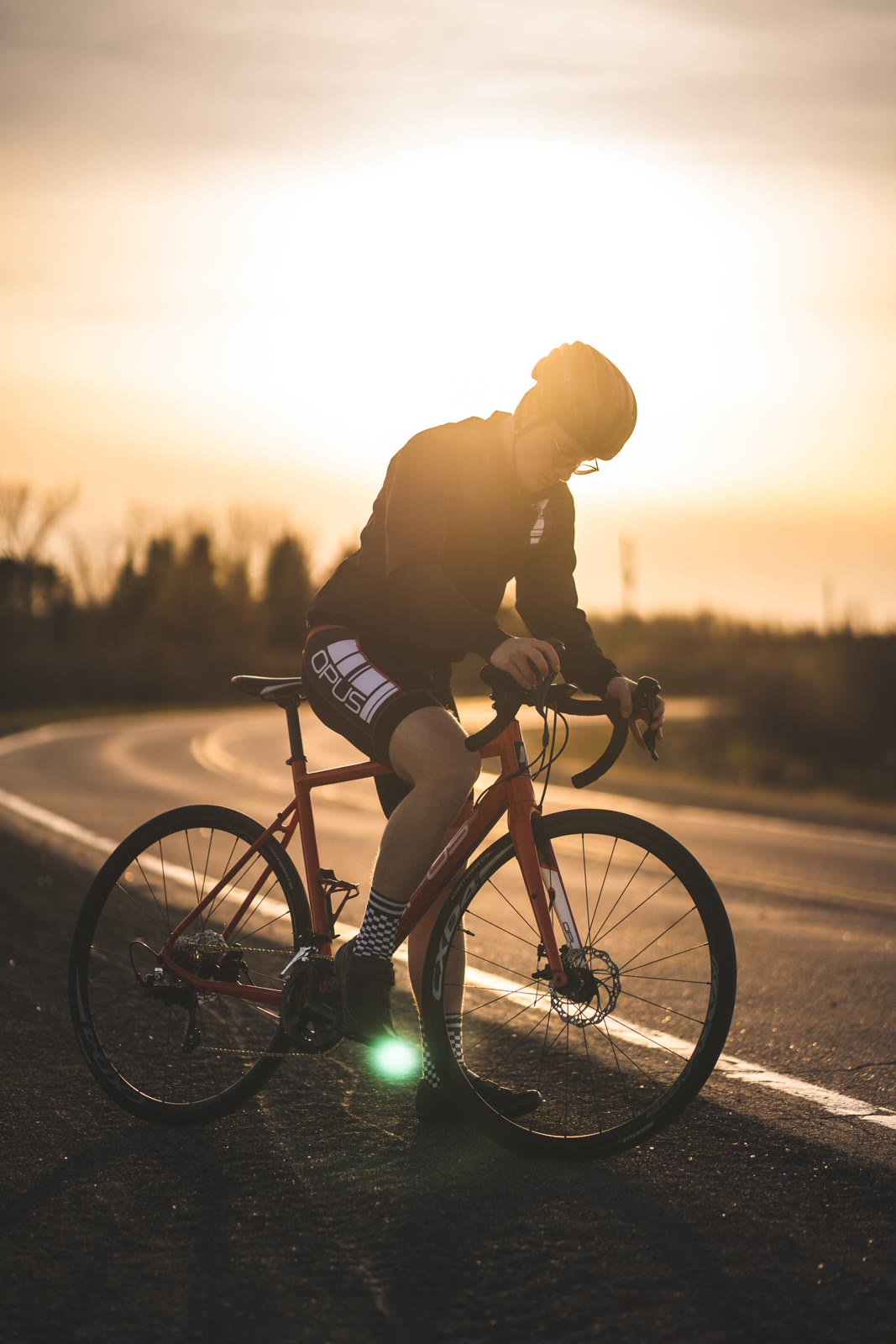 A road cyclist leaning into a curve at sunset.