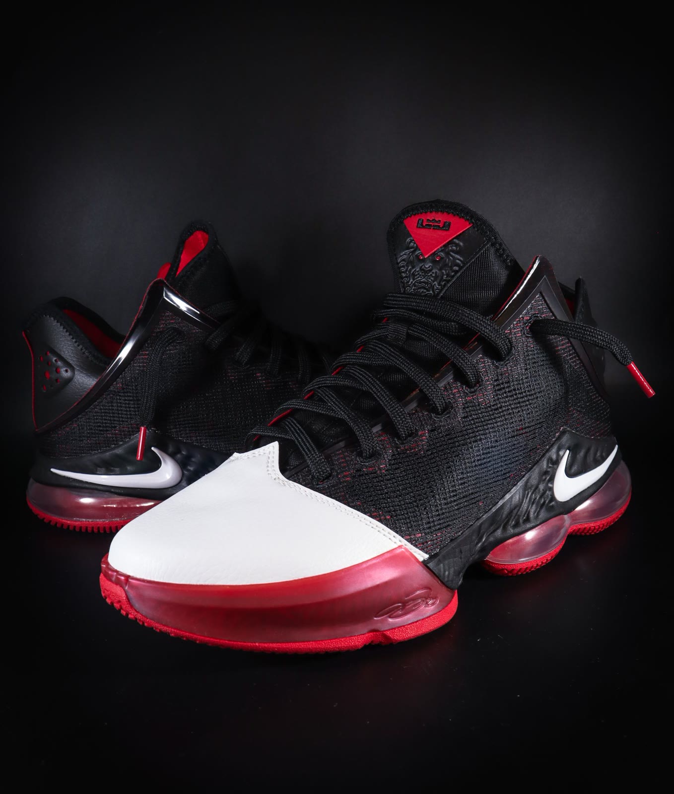 Red and black athletic sneakers photographed against a dark background.