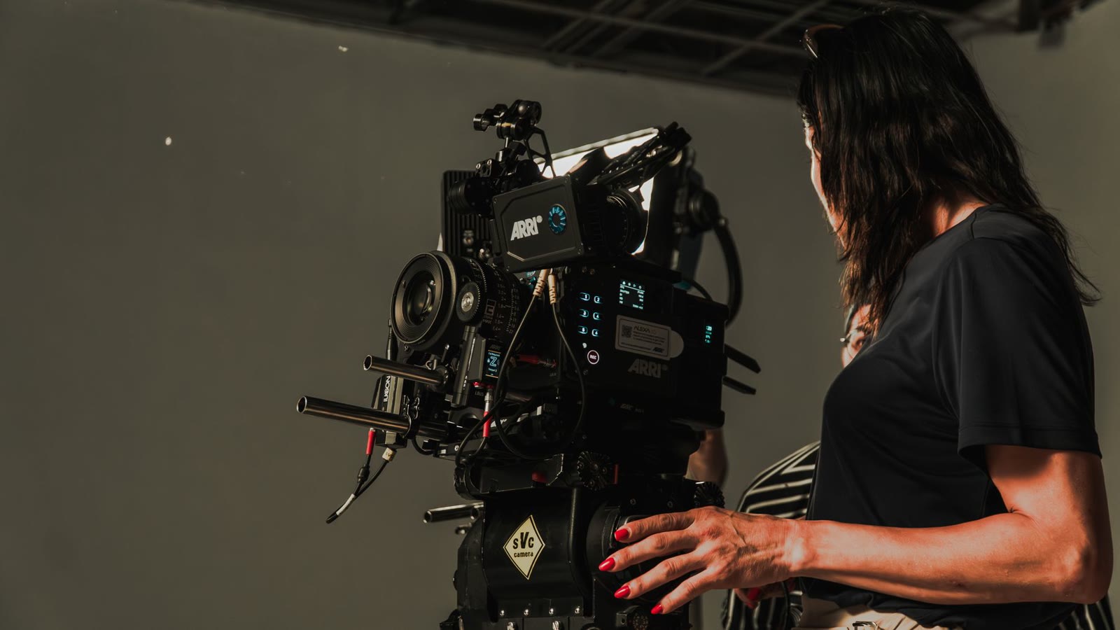 A film crew operating a cinema camera rig in a dark studio.